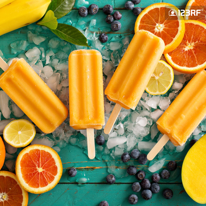 Stock Photo - Mango banana popsicles on ice with fresh fruits and berries