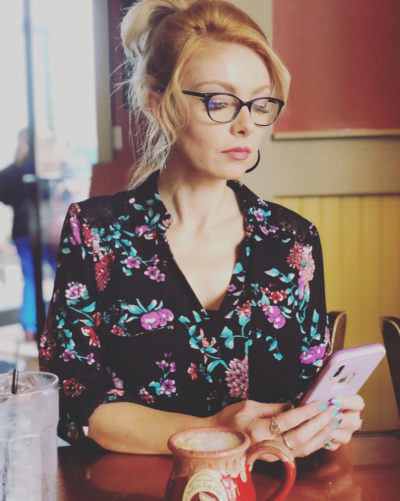 A woman looks at her phone reviewing ashley madison profiles