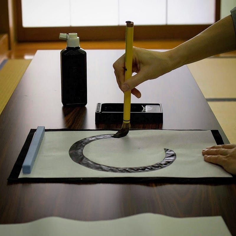 A circle is being drawn with an ink brush on a white canvas, part of calligraphy practice at Zenpoji Temple in Tsuruoka, Yamagata Prefecture.