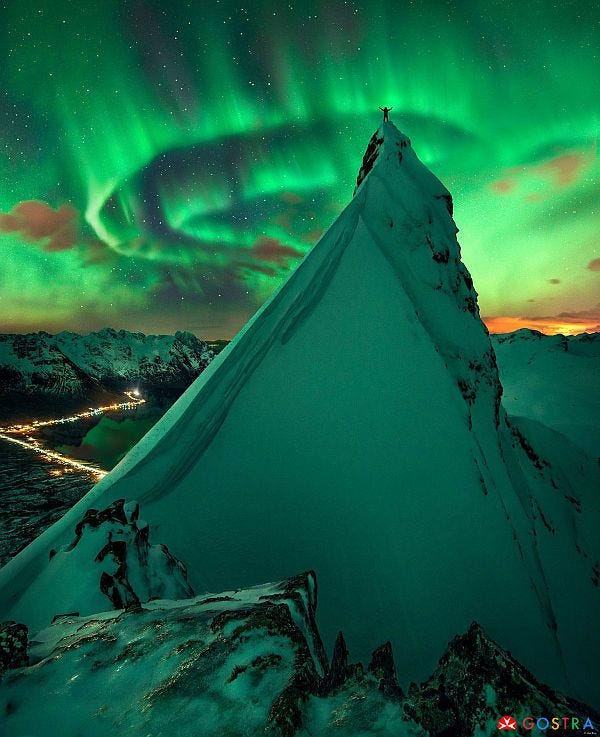 Northern lights above the mountain with a human on top