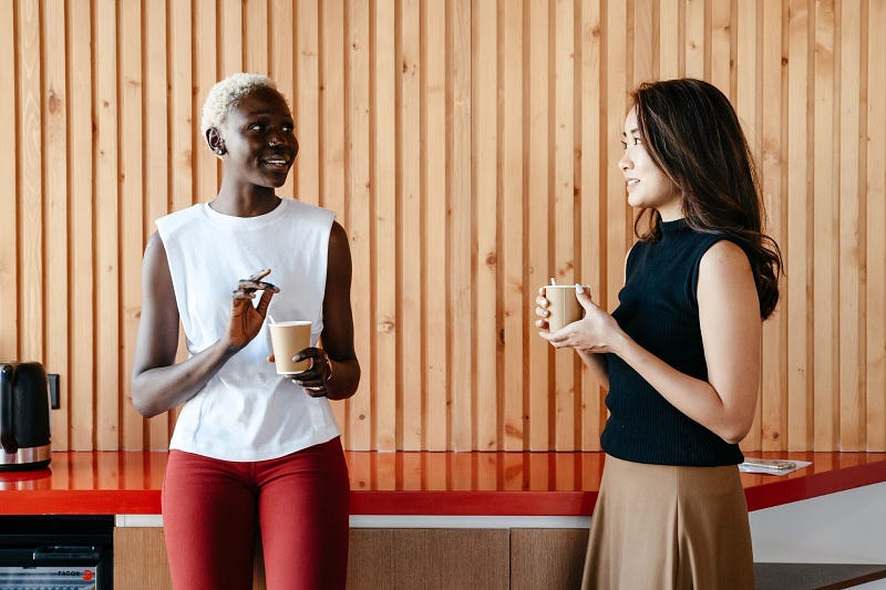 two people talking to each other while holding a cup of coffee