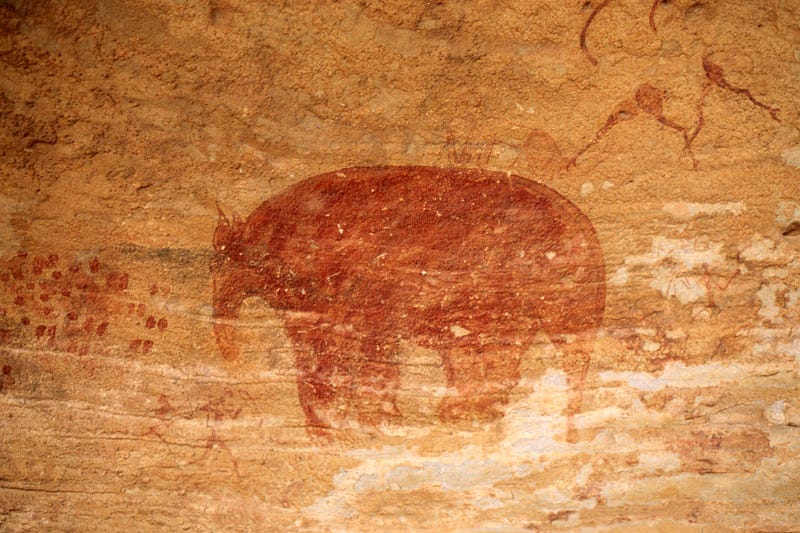 A Mastodon cave painting, depicting a reddish Mastodon on a sand-colored rock wall.