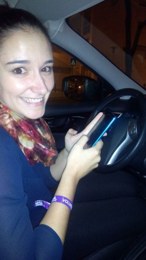 Woman on the driver side with a phone looking at the camera smiling