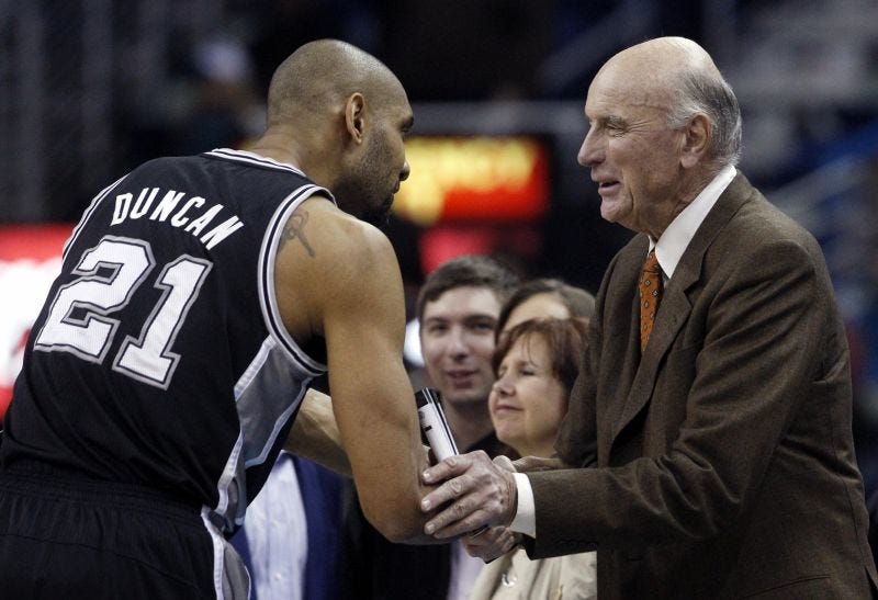 Bob Pettit (right) shakes hands with San Antonio Spurs power forward Tim Duncan.
