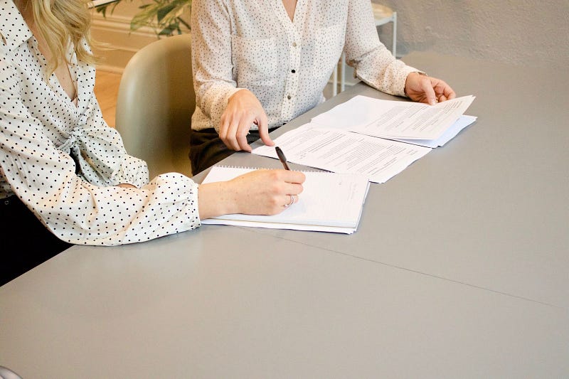 two people sitting in front of a table with papers