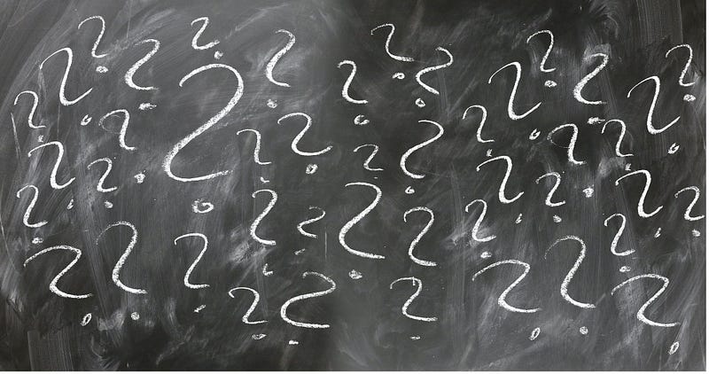 white question marks written on a black chalkboard
