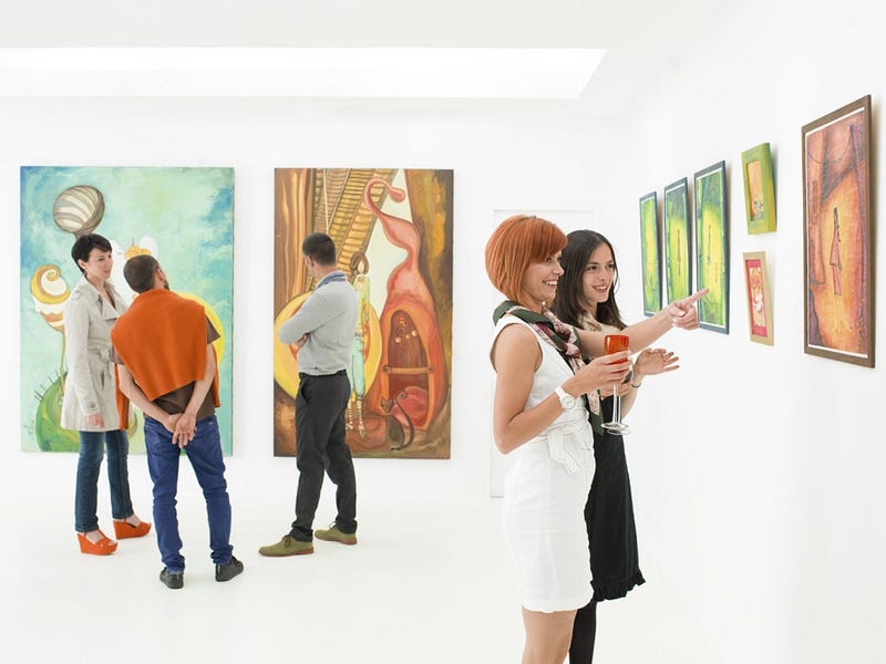 people in an art gallery talking about the colorful paintings displayed on walls