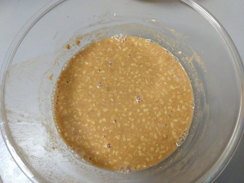 A light brown liquid with pieces of peanuts floating in it, contained in a glass bowl.