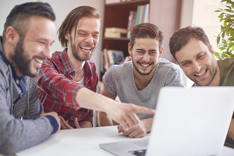 men laughing at something on the laptop
