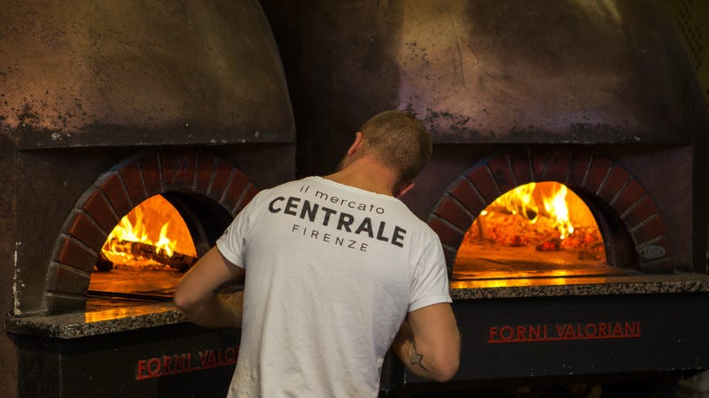 Hombre frente a un horno de pizza caliente