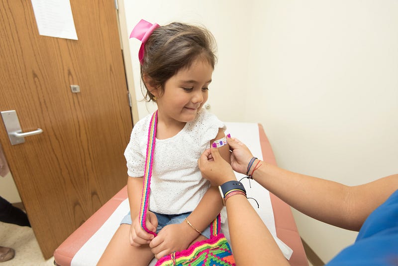 Young girl receiving band aid in doctors office