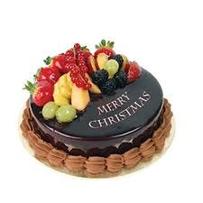 A brown and red Christmas cake with fruit pieces on top made with added alcohol and rum