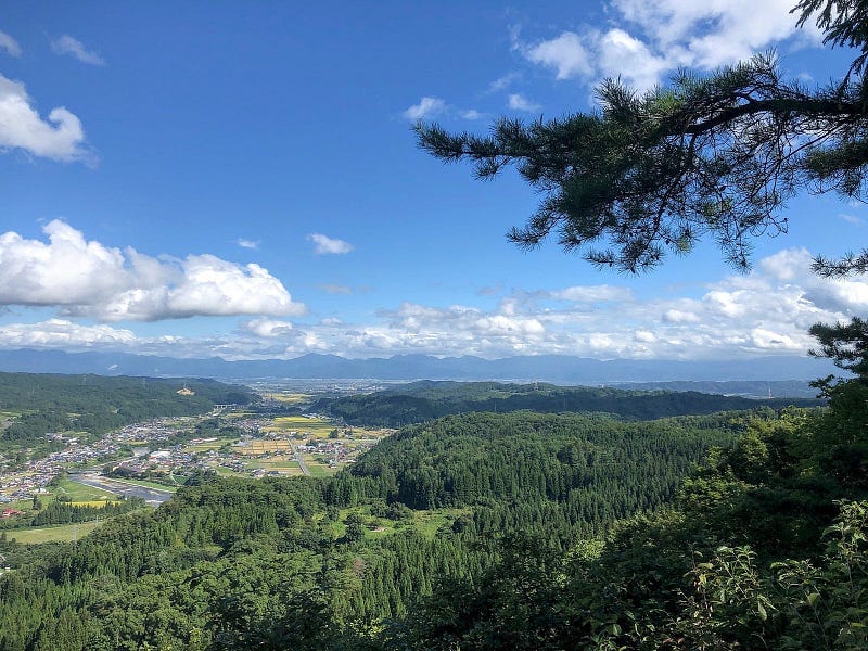 Bright blue sky, mountain forests, and the small township of Nishikawa seen from the summit of Tengu-yama.