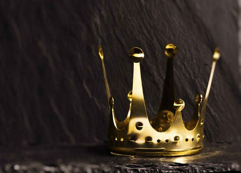 Royal gold crown on dark stone surface. Concept of wealth, success and kingdom.