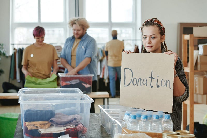 a person holding a cardboard with the word "Donation" written on it