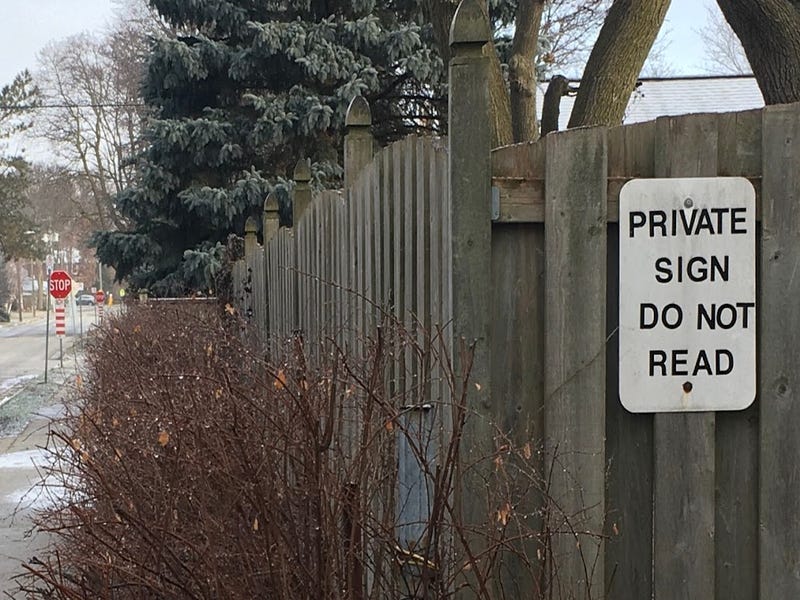 funny sign on homeowner’s fence reading “Private sign do not read”