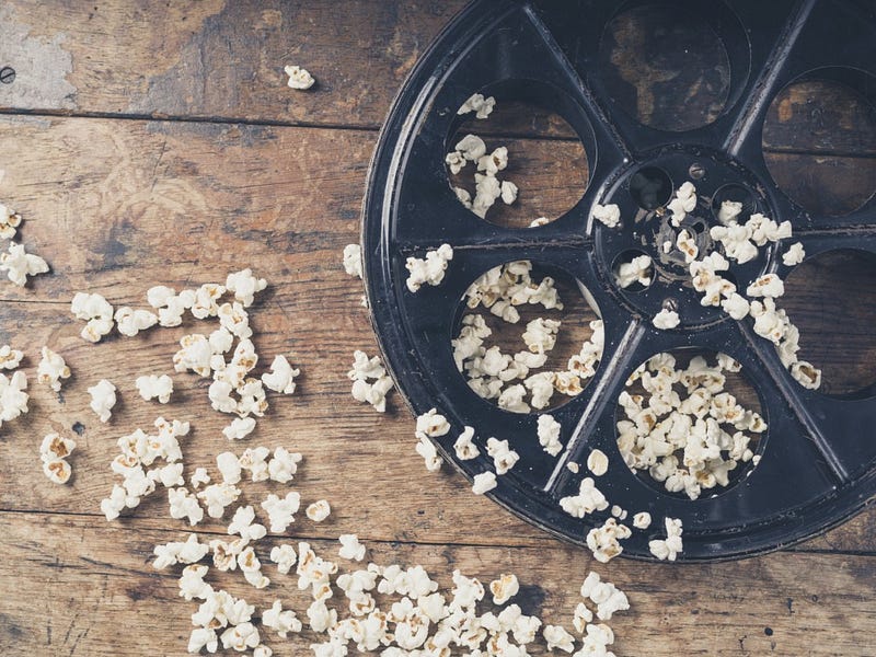Cinema concept of vintage film reel with popcorn on wooden surface