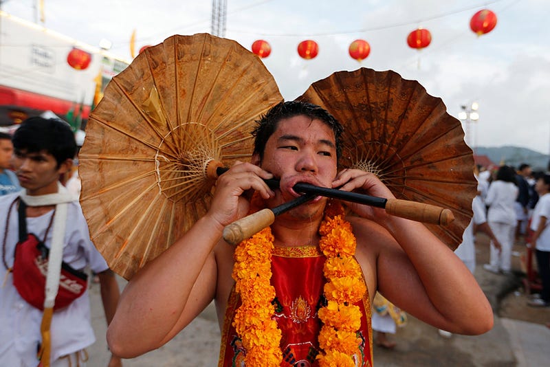 A devotee of the Chinese Samkong Shrine walks with two umbrellas pierced on his face during a procession celebrating the annual vegetarian festival in Phuket, Thailand October 4, 2016. REUTERS/Jorge Silva