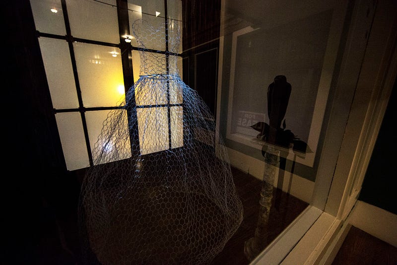 A wire-structure of a dress is illuminated by light in a display window in Sycamore Square in Fairhaven. April McAllister, property manager of the building, says she has encountered supernatural spirits throughout the building's floors.