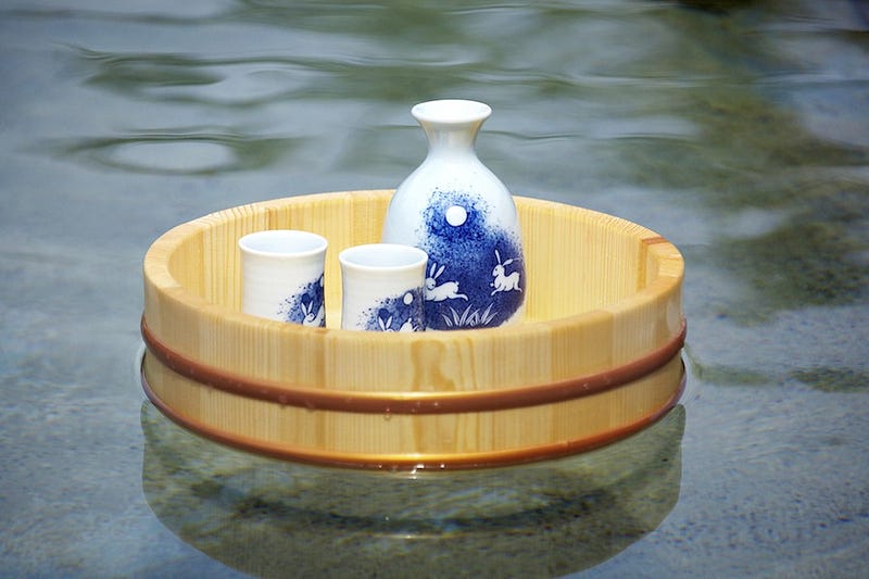 A bottle of sake floats on top of a bathing bucket