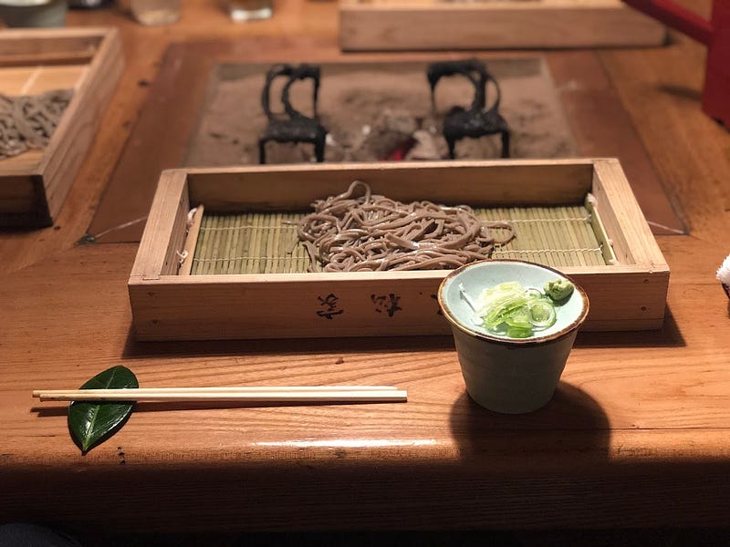 Soba Noodles in front of an Irori hearth with chopsticks laid on a deep green leaf at Omatsuya, a restaurant in the outskirts of Sakata City, Yamagata Prefecture near Mt. Kyogakura, one of the 100 Famous Mountains of Yamagata