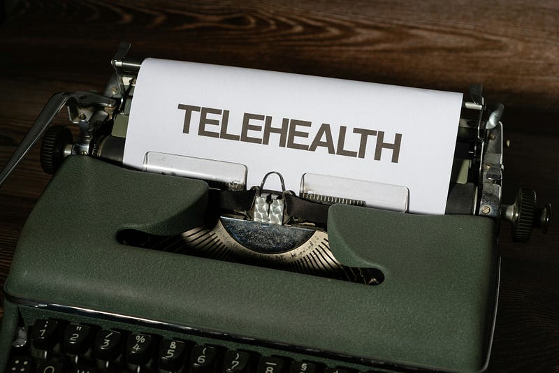 A old-fashioned typewriter with a piece of paper reading “TELEHEALTH.”