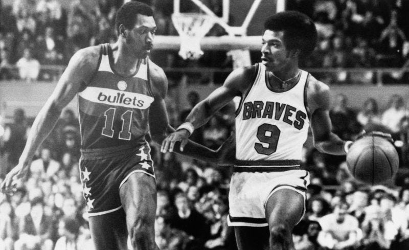Randy Smith (right) dribbles up the court while Elvin Hayes of the Washington Bullets defends.