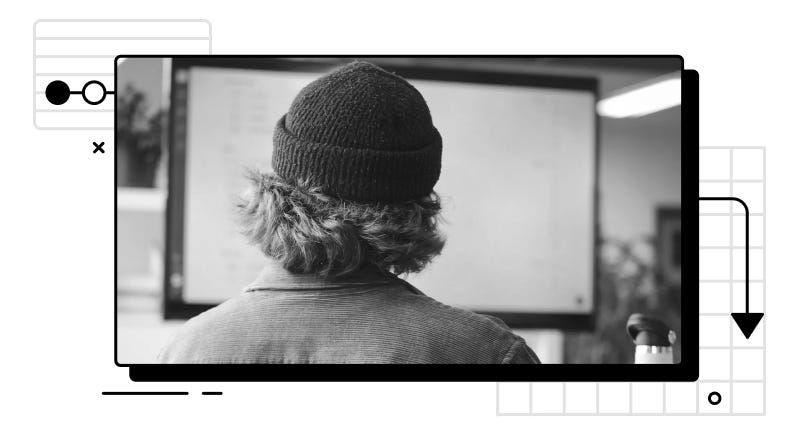 Person wearing a hat staring at an out-of-focus computer monitor.