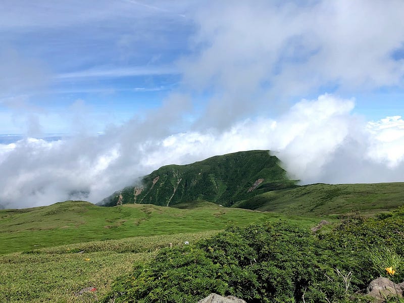 The green hills of the Hokodate Trail of Chokai-san (Mt. Chokai) under a cloudy sky.