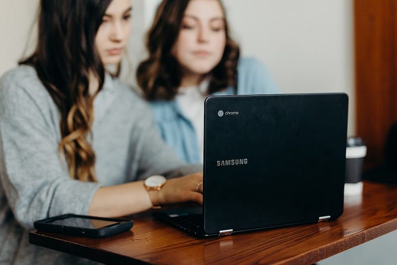 Two colleagues working on a problem behind a laptop