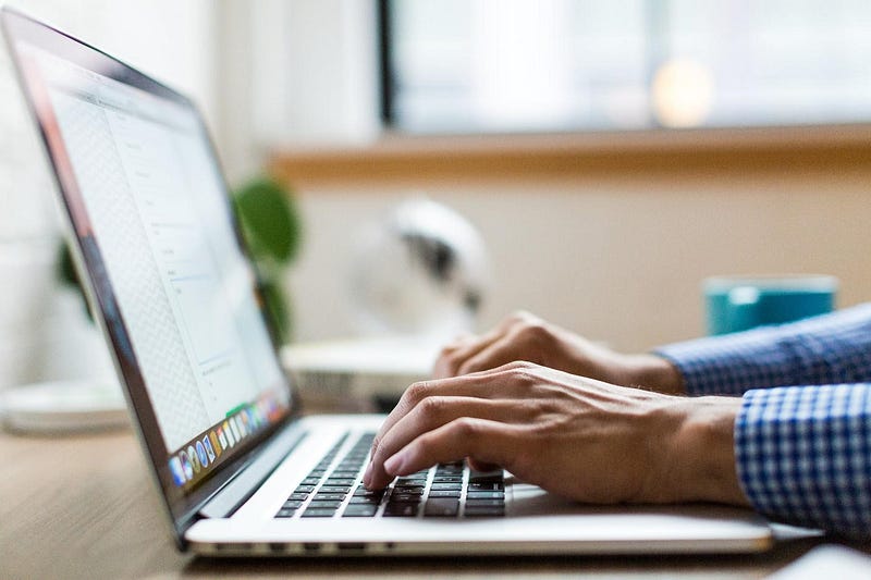 A person typing an email on a laptop