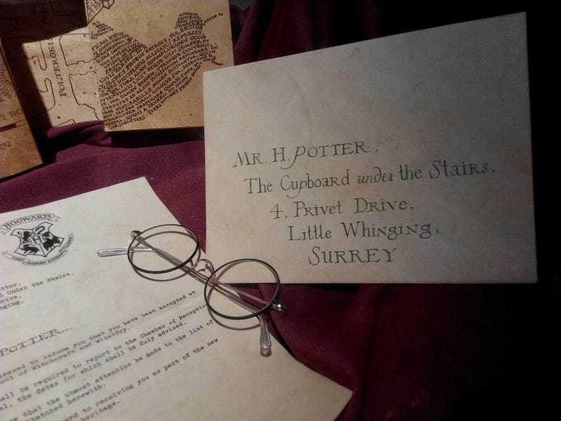A picture of a replica "Harry Potter" Hogwarts acceptance letter, Marauder's map, and a pair of round-rimmed glasses used as an image in "Reflection: Harry Potter Series by J.K. Rowling" by Alina Happy Hansen