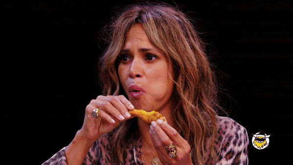 Halle Berry suffering a little bit and blowing out air as she’s biting into a chicken wing