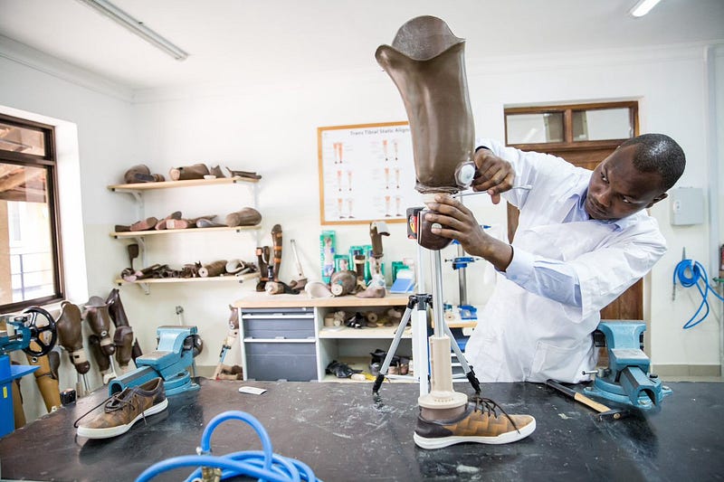 A man works on a lower-limb prosthetic in a lab in Tanzania.
