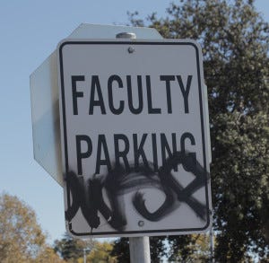 Graffiti mars a parking sign, a common sight in the Laney College lot.