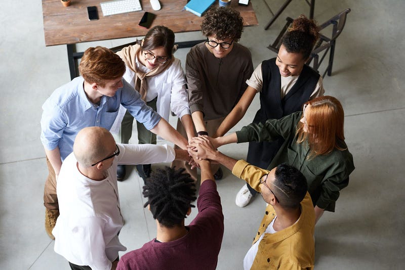 eight small business administration team members gathered in a circle with their hands together