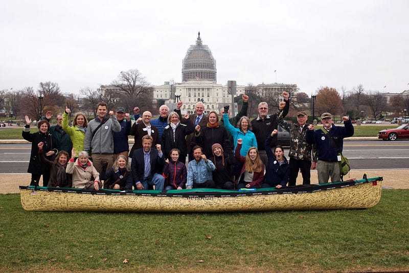 Dave and Amy Freeman pose with friends and fellow advocates around the canoe that took them on their 2,000 mile jouney.