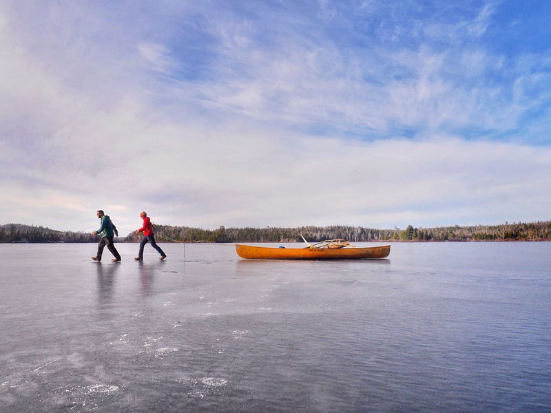 Dave and Amy pull their canoe across a frozen lake.