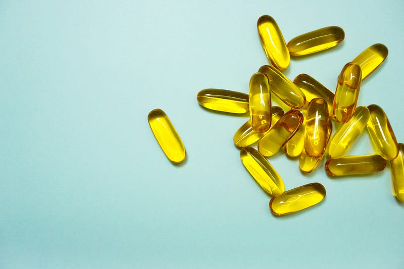 A pile of golden, oblong fish oil capsules.