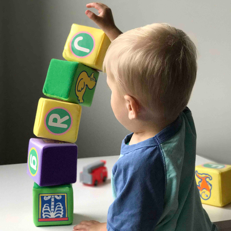 Small child stacking toy blocks with letters on them