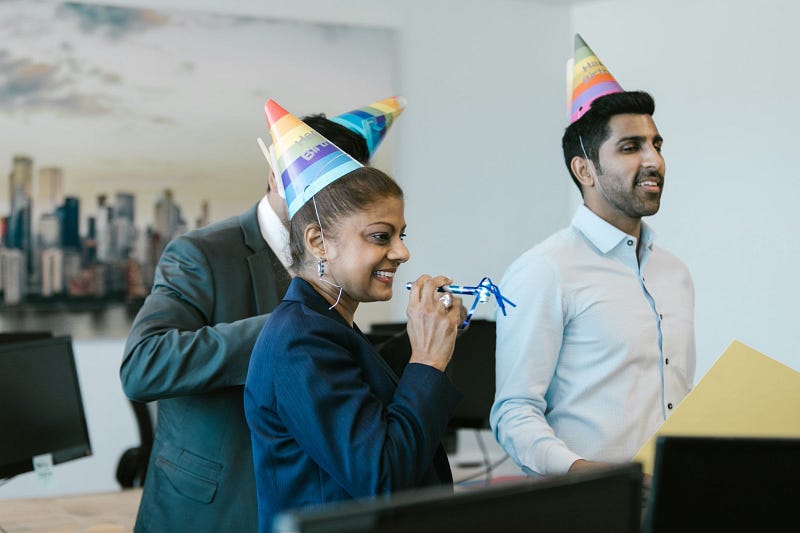three employees wearing party hats