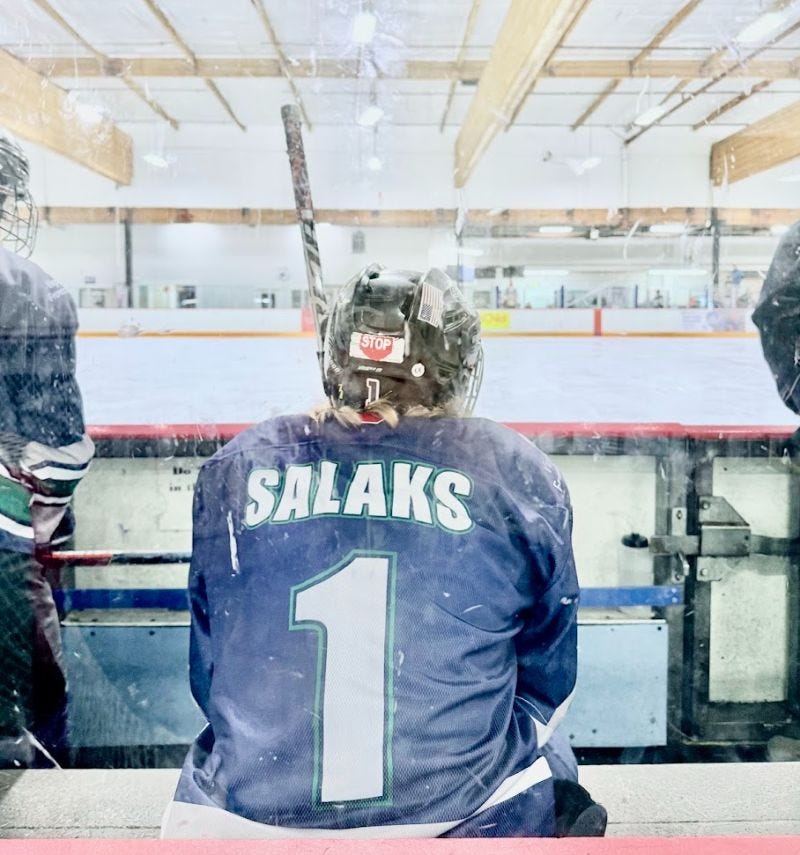 Hockey player sitting on the benching looking at the rink