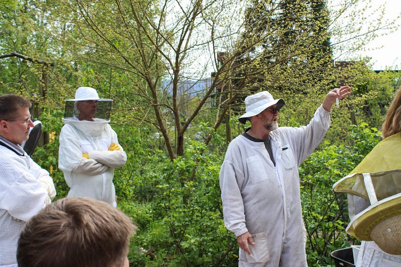 Jaross holds up a cage used to separate the queen bee from the reset of the honeybees in commercial packages of bees ordered from breeders. He explains how the queens included in packaged bees need to be introduced to the colony before they can be released from their cage.