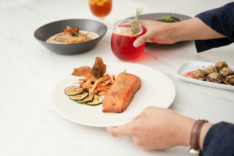 A dinner plate with salmon and some vegetables.