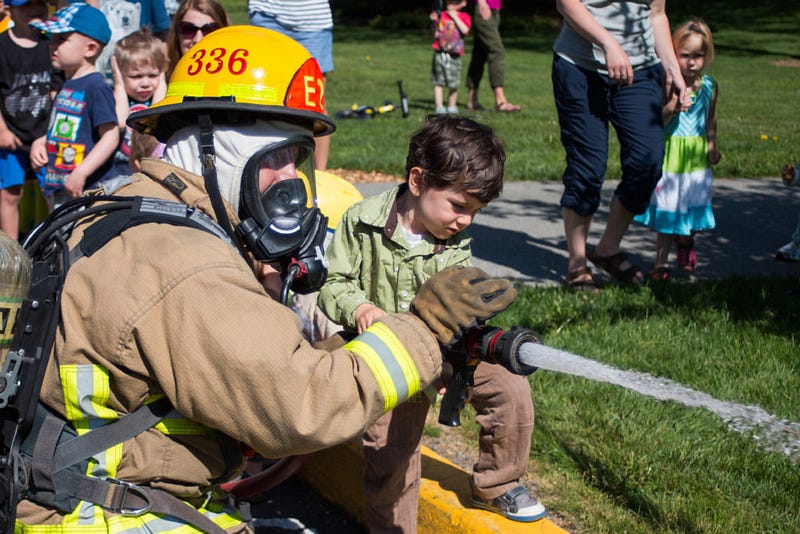 Fully dressed in bunker gear, McDonald helps 4-year- old Jonah Hawthorne operate a fire hose at his birthday party at Fairhaven Park on Saturday, May 7. The firefighters took this opportunity to interact and educate Jonah and his friends on fire safety. “Firefighter John” slowly changed into his bunker gear, reminding the kids that he is still Firefighter John even though he looks like a scary monster. “A lot of the time, in a fire, kids get scared of us and hide,” McDonald explains. “Can we all practice yelling ‘help, help, I’m over here!’ like you’d do if you were in trouble?”