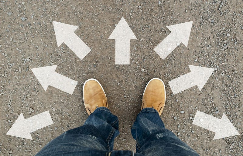 Yellow boots on the road. A man standing on the road. The road arrow