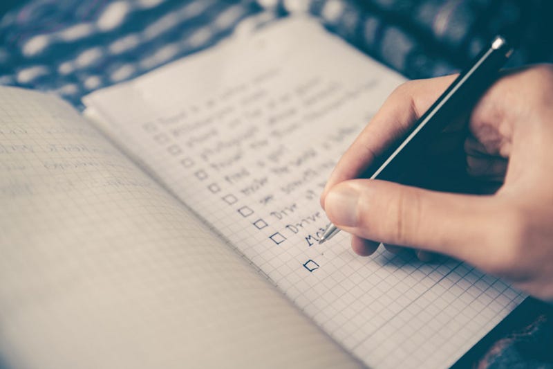 A hand writing down a checklist on a notebook