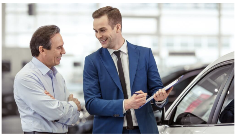 a guy selling a car to another guy and smiling while doing so
