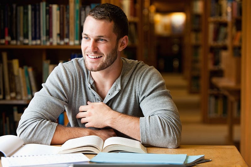 Smiling male student working in a library