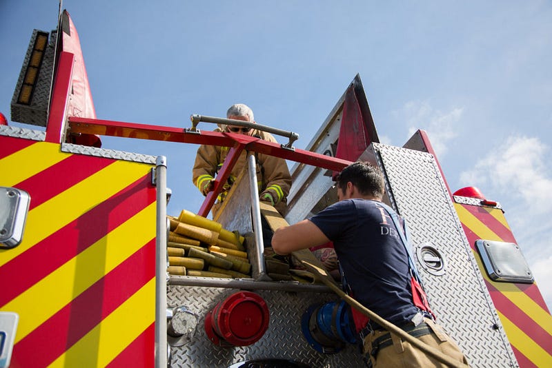 Dowdy feeds a fire hose to firefighter Bob Coston who lays the hose back into place on top of the fire truck. “The worst part about training is you get 45 minutes of cleanup for 15 minutes of training,” Dowdy says as he works to put away fire hose.